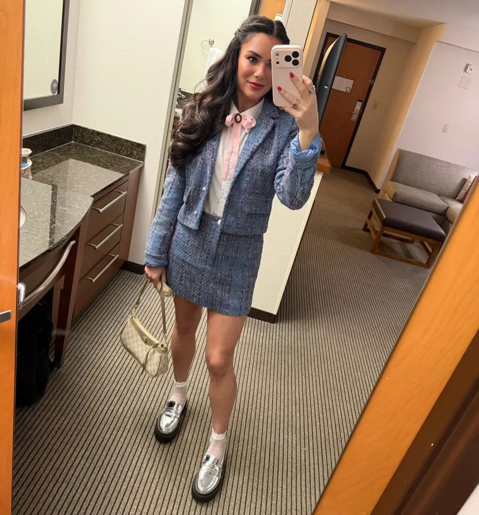Susanne in a blue flecked tweed blazer and matching mini skirt over a white shirt with a pink bow brooch, sheer socks and metallic silver loafers