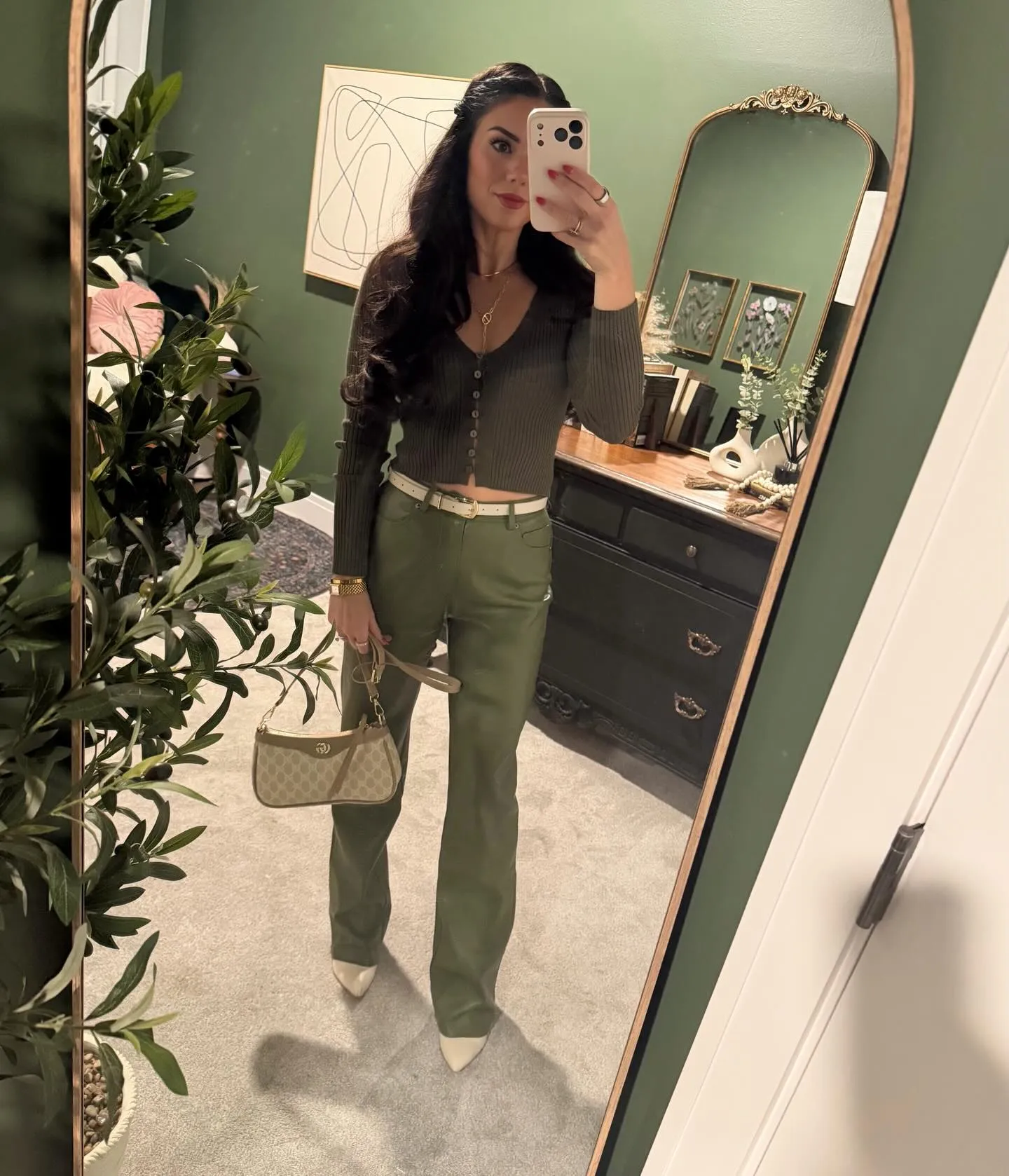 Susanne in an olive ribbed cardigan top and olive leather pants with a white belt, monogram shoulder bag and white pointed pumps
