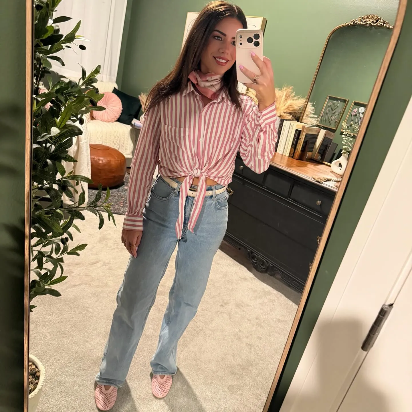 Susanne in a pink striped button-down knotted at the waist with light-wash jeans, pink floral neck scarf and pink mesh flats