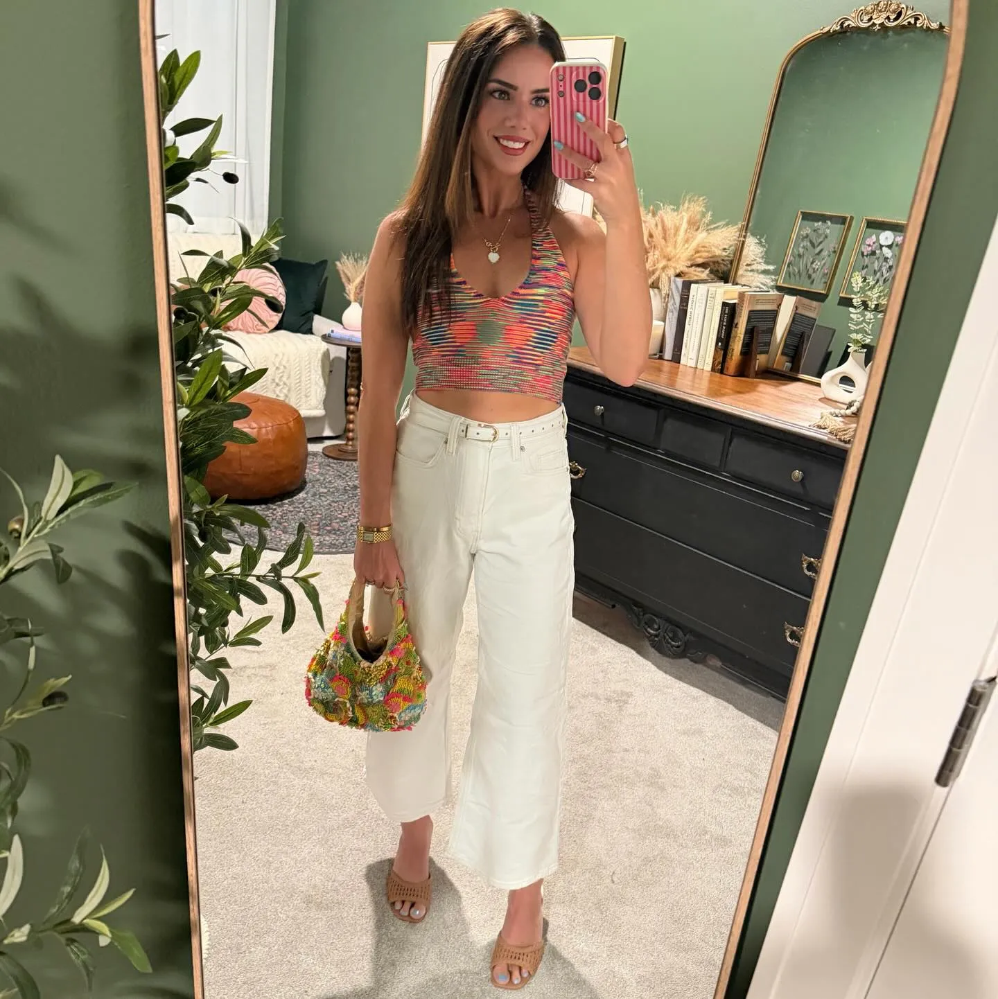 Susanne in a multicolor knit halter crop top and high-rise white wide-leg jeans with a white belt, colorful beaded bag and tan woven heels