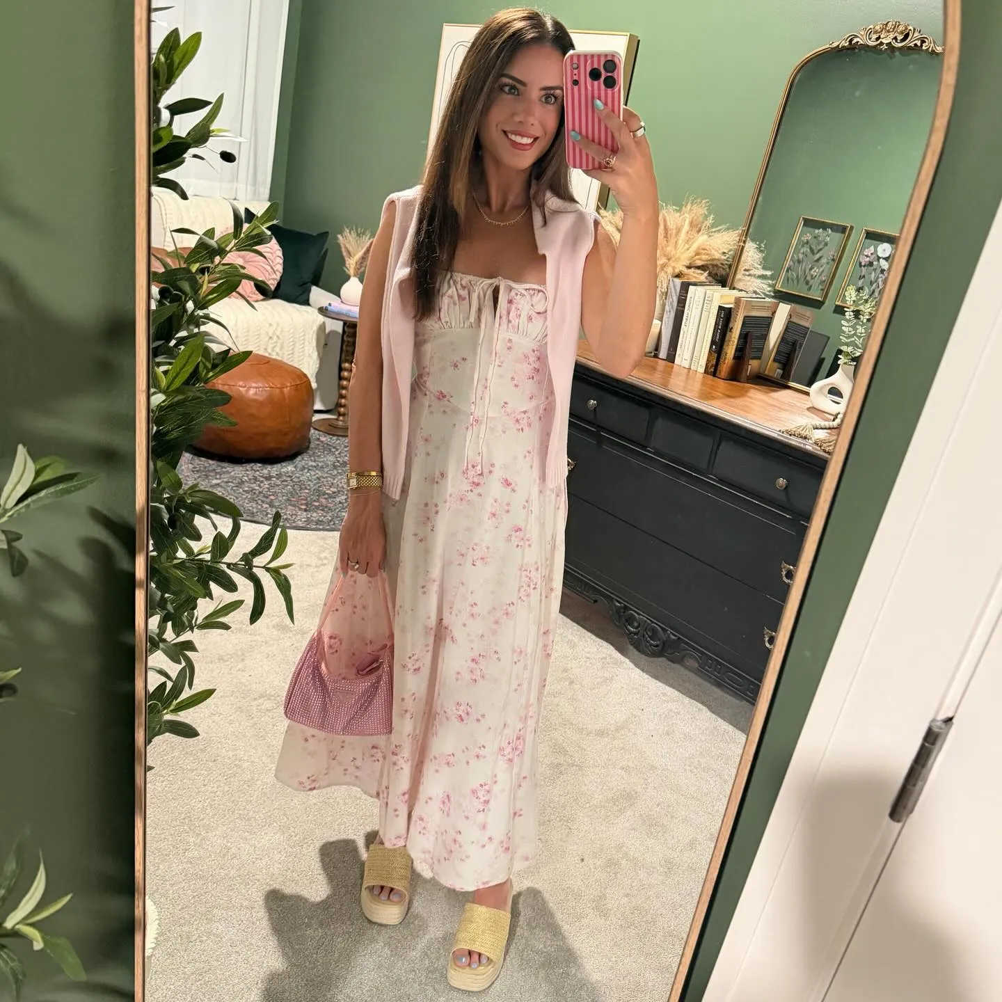 Susanne in a pink and white floral midi dress with a pink cardigan over her shoulders, sparkly pink mini bag and tan raffia platform slides