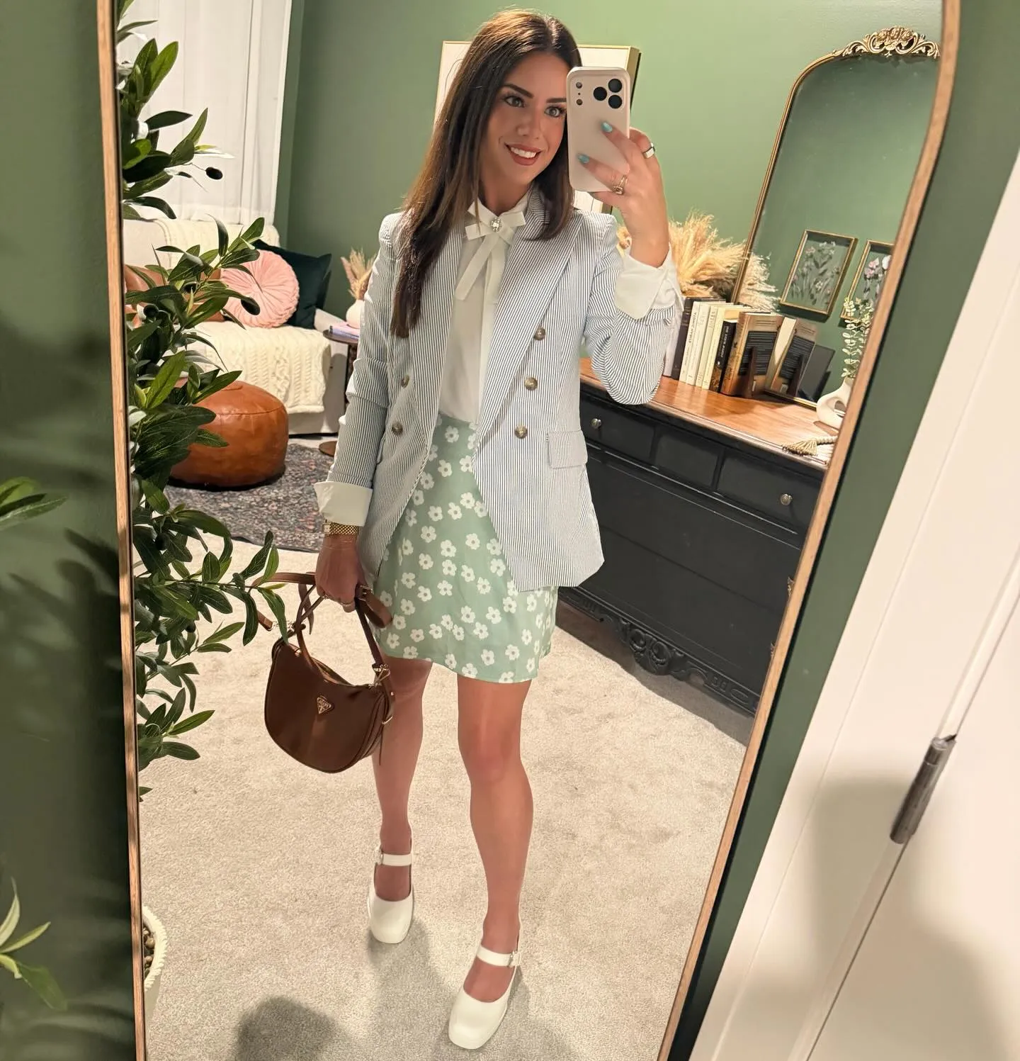 Susanne in a blue pinstripe blazer over a white shirt with a bow brooch, mint green floral skirt, brown hobo bag and chunky white Mary Janes