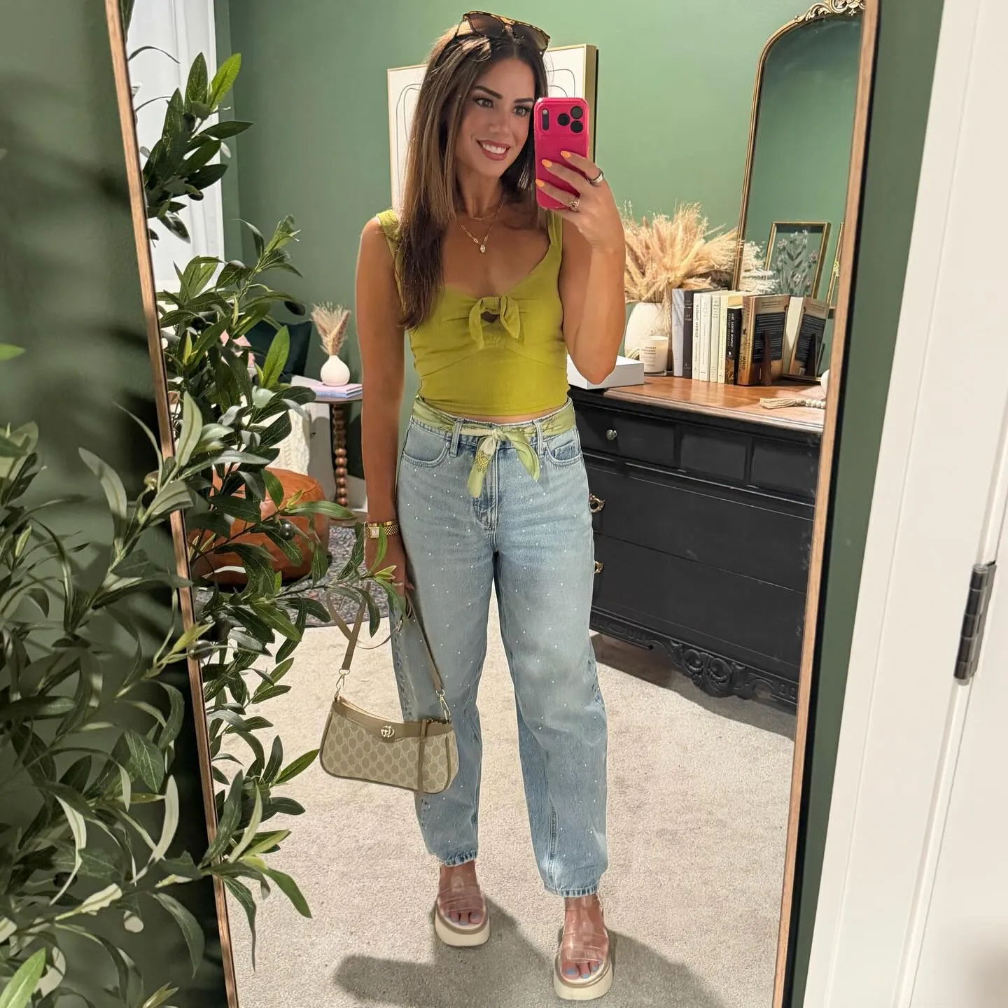 Chartreuse green tie-front tank with light-wash rhinestone-studded barrel jeans, a green scarf tied at the waist, tan logo shoulder bag and clear platform sandals.